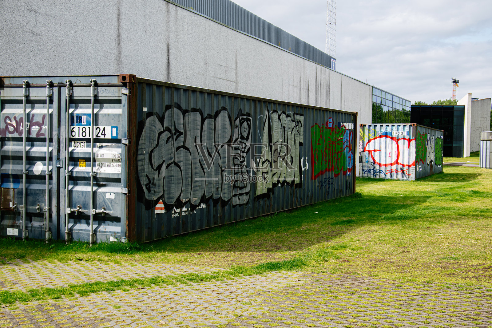 雷克雅未克的城市建筑和绿意中涂鸦覆盖的工业集装箱照片摄影图片