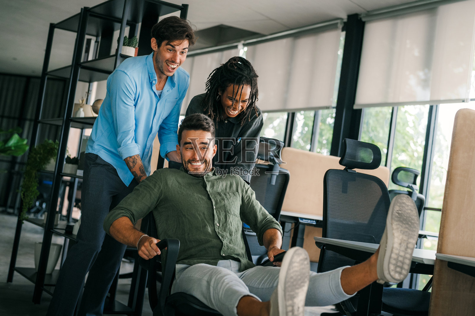 兴奋的多元化员工在工作休息时欢笑，享受有趣的活动，友好的创意工作者照片摄影图片