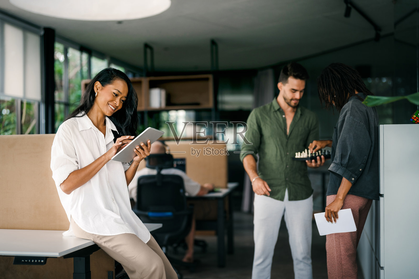 多元化的两位商务人士在公司办公室内边走边使用平板电脑交谈。照片摄影图片