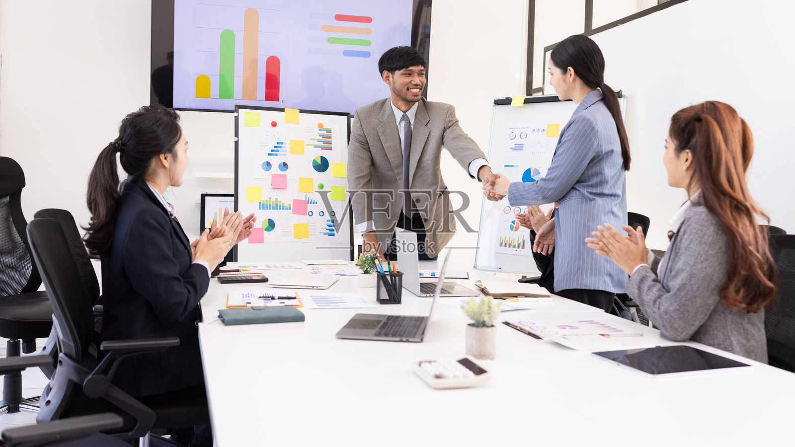 一群商务人士在会议室握手并共同合作，进行仪表板分析和数据管理。照片摄影图片