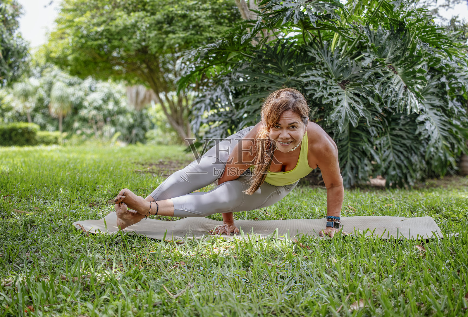 无龄力量：快乐的成熟的女性在瑜伽手臂平衡姿势中照片摄影图片