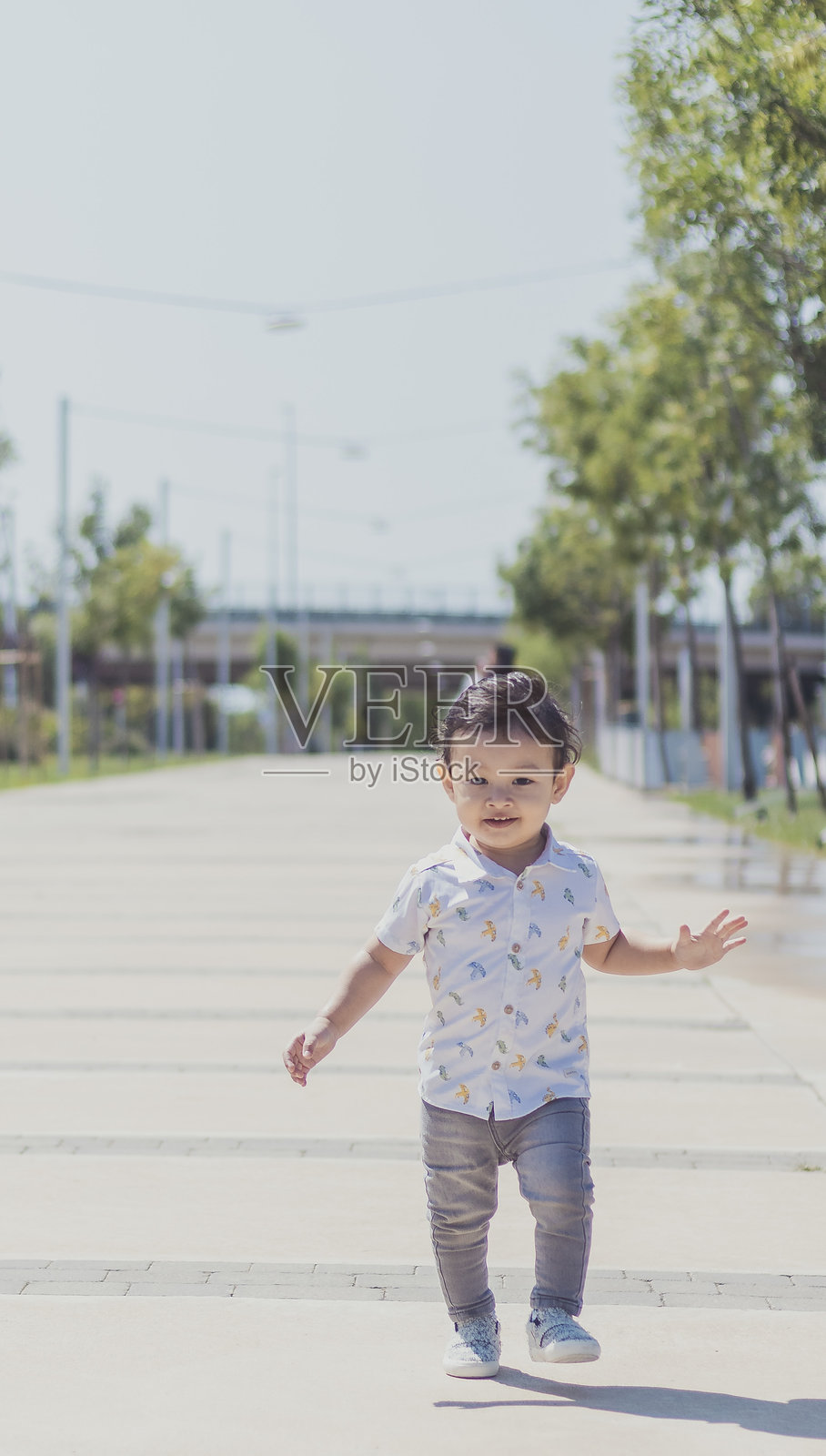 年轻孩子在阳光明媚的小路上快乐地奔跑，周围是绿树和现代建筑。照片摄影图片