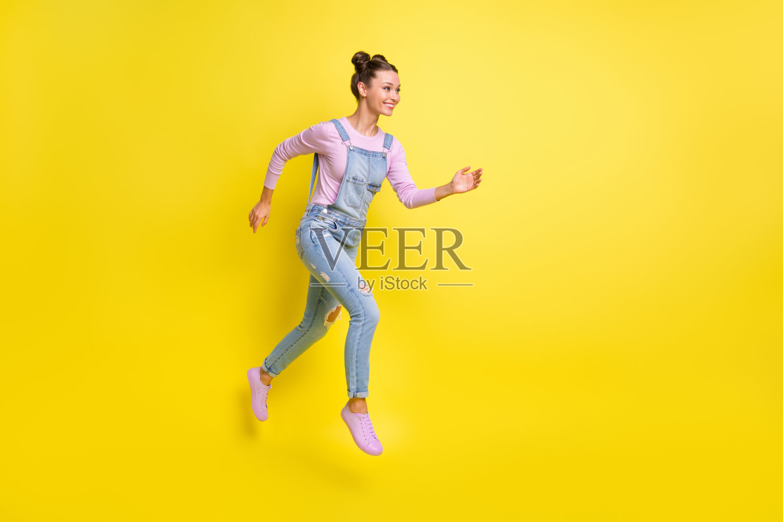 快速奔跑的女孩的个人头像，穿着牛仔工装鞋，背景为空旷的黄色。照片摄影图片
