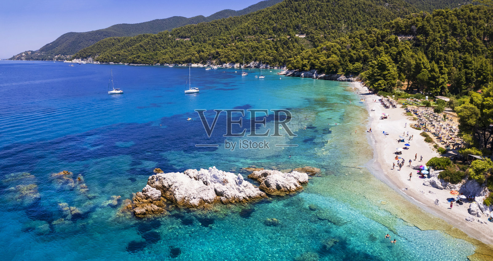 希腊夏季旅游目的地。米利亚是斯科佩洛斯岛上最美丽的海滩之一，斯波拉德群岛。高角度无人机视角下的碧蓝海水，白色卵石和松树。照片摄影图片