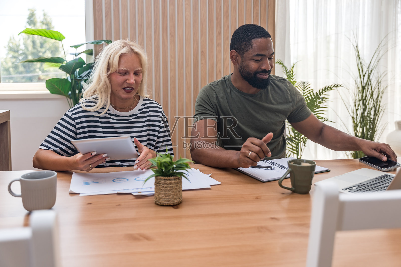 一对年轻情侣在家办公，共同创业新全球业务，休闲的男商人和女商人在用笔记本电脑和文件处理财务和经济事务。照片摄影图片