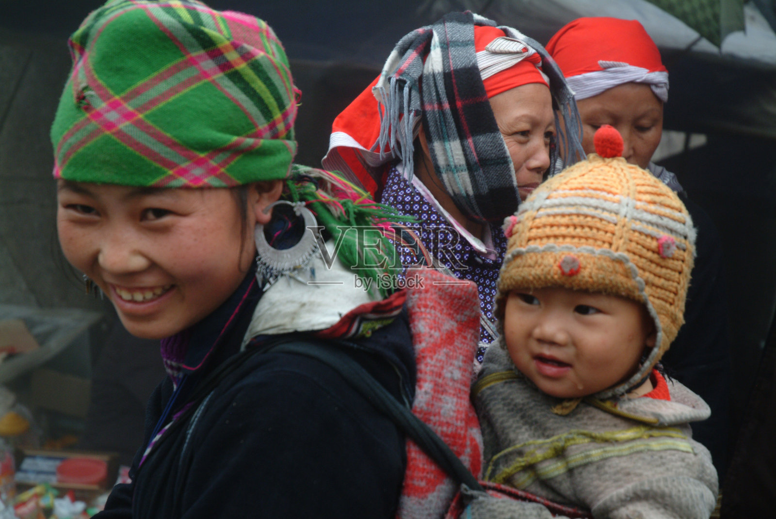身穿传统服饰的苗族妇女抱着孩子。照片摄影图片