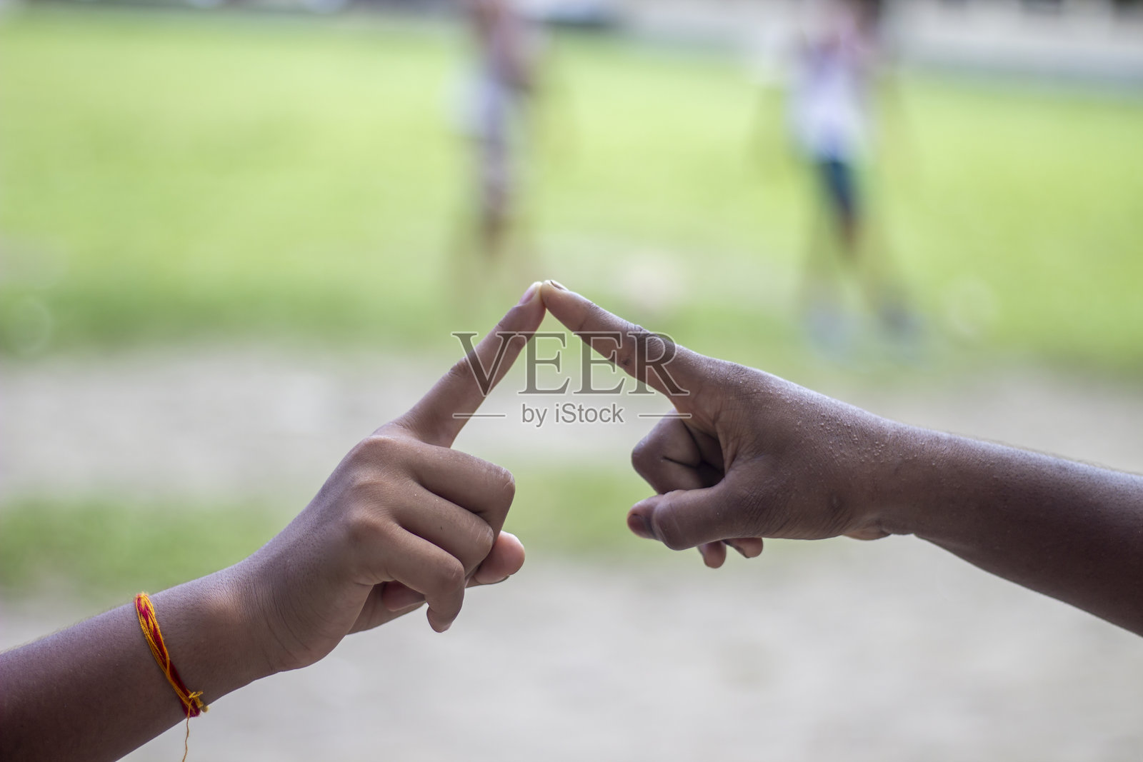两个男人做出爱心手势，背景模糊为绿色。照片摄影图片