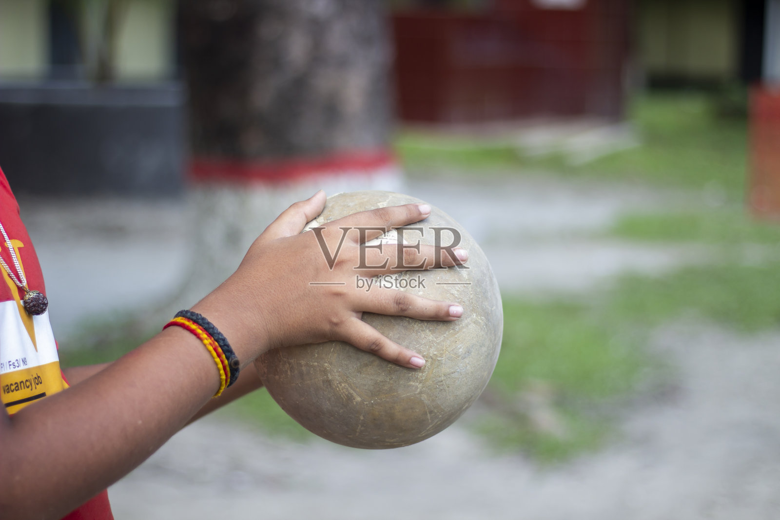 一个男人手持足球，背景模糊不清。照片摄影图片