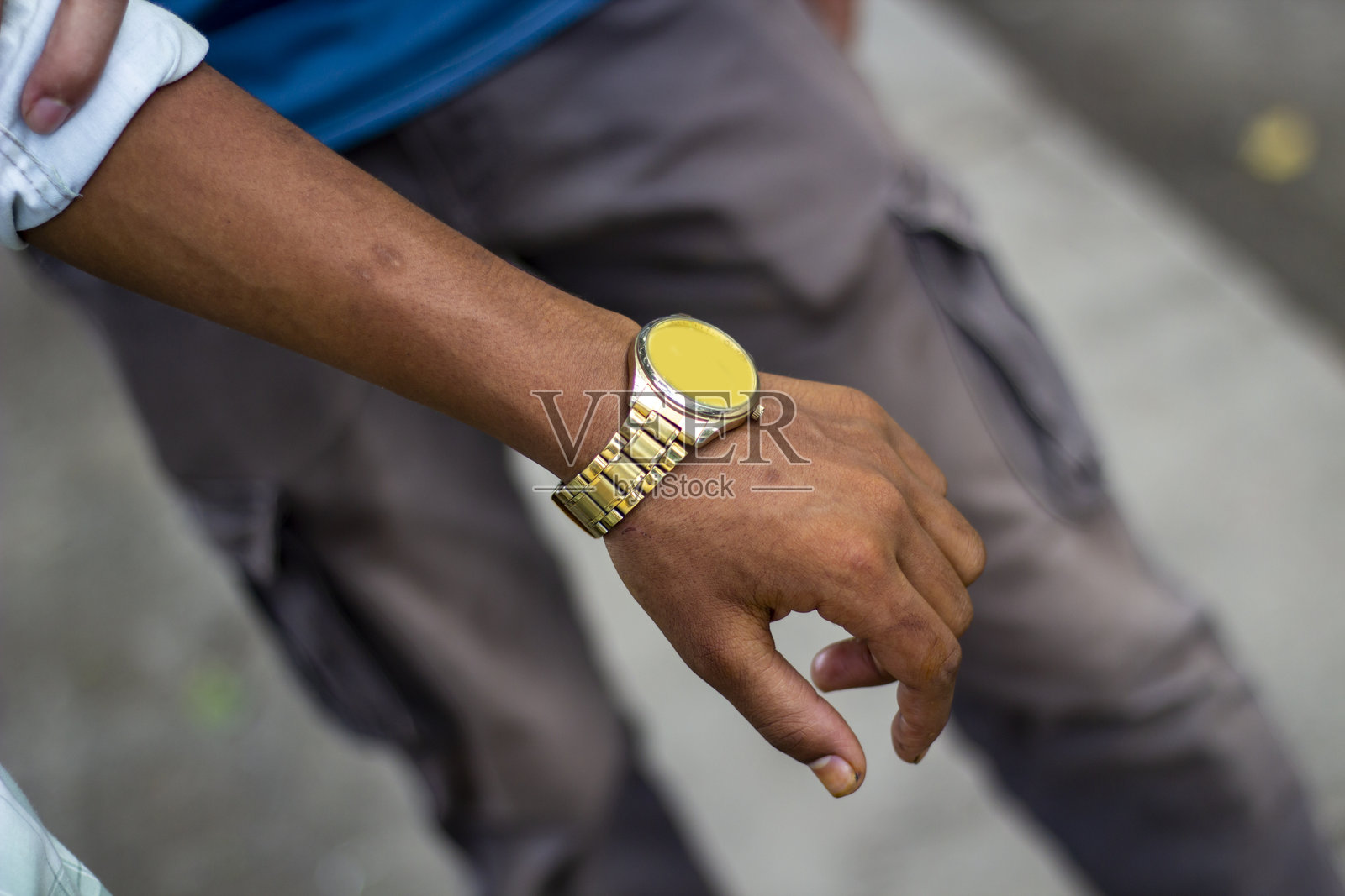 一个男人戴着手表，背景模糊不清。照片摄影图片