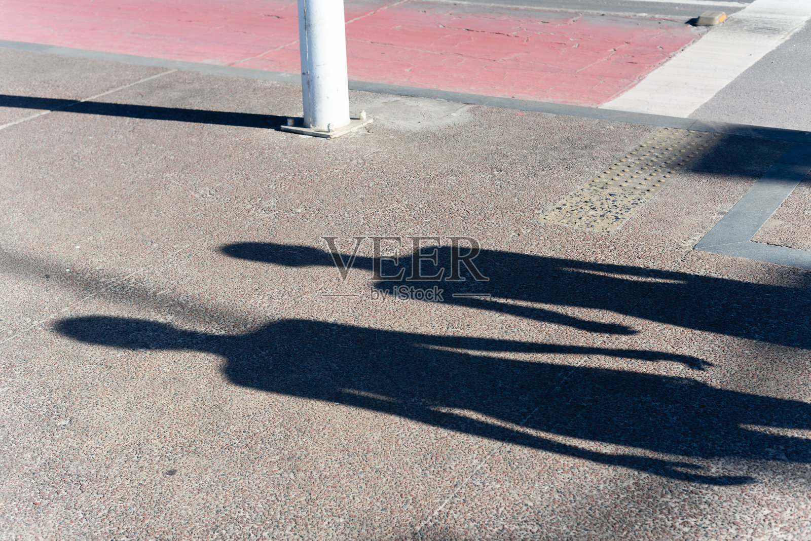 两个人的影子投射在地面上。照片摄影图片