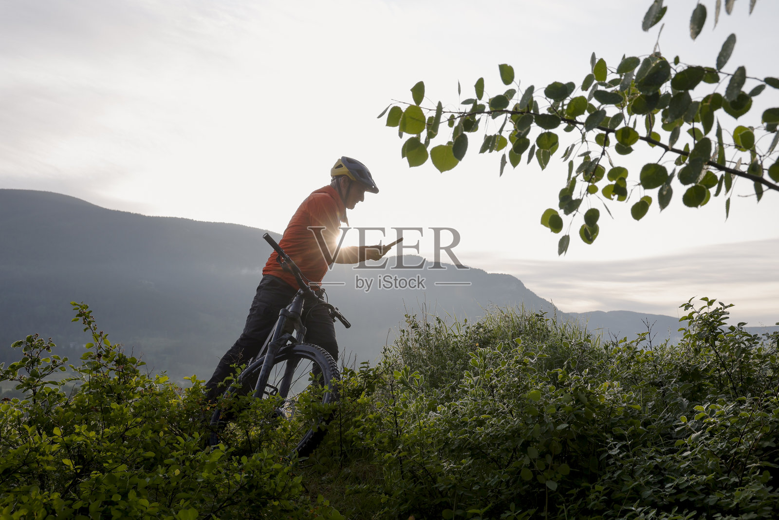 成熟男性在山上骑电动山地车时暂停使用手机照片摄影图片