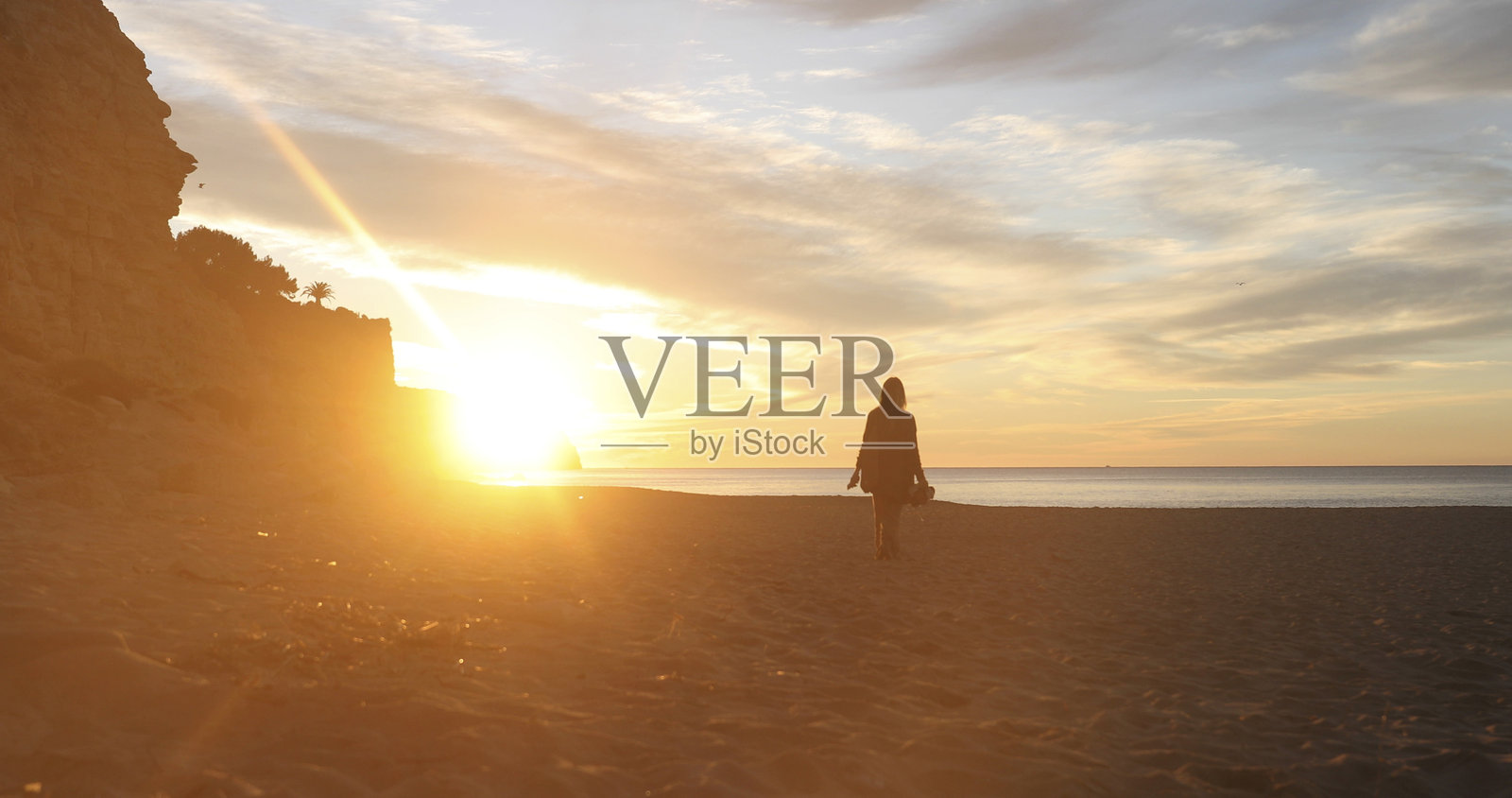 年轻女性在日出时分探索空旷的海滩照片摄影图片