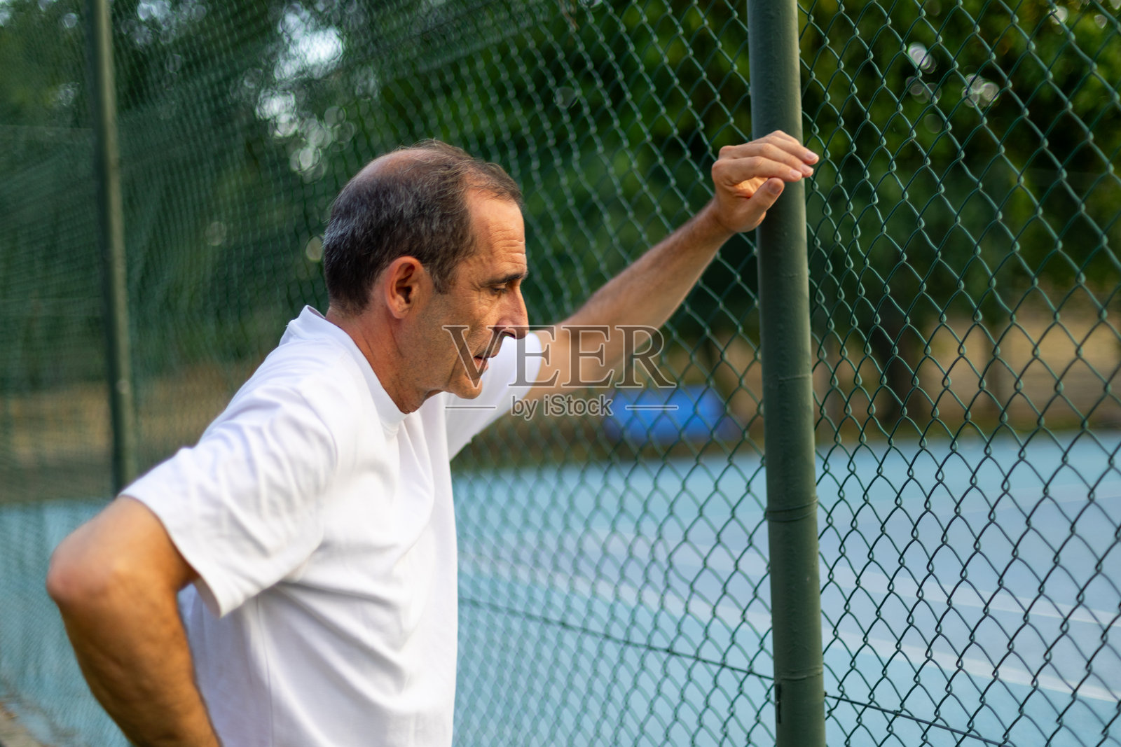 疲惫的网球运动员在比赛后靠在网子上照片摄影图片