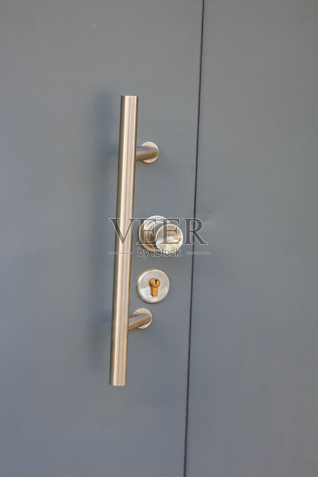 现代灰色入口门，配有金色把手和安全锁，位于现代建筑中照片摄影图片