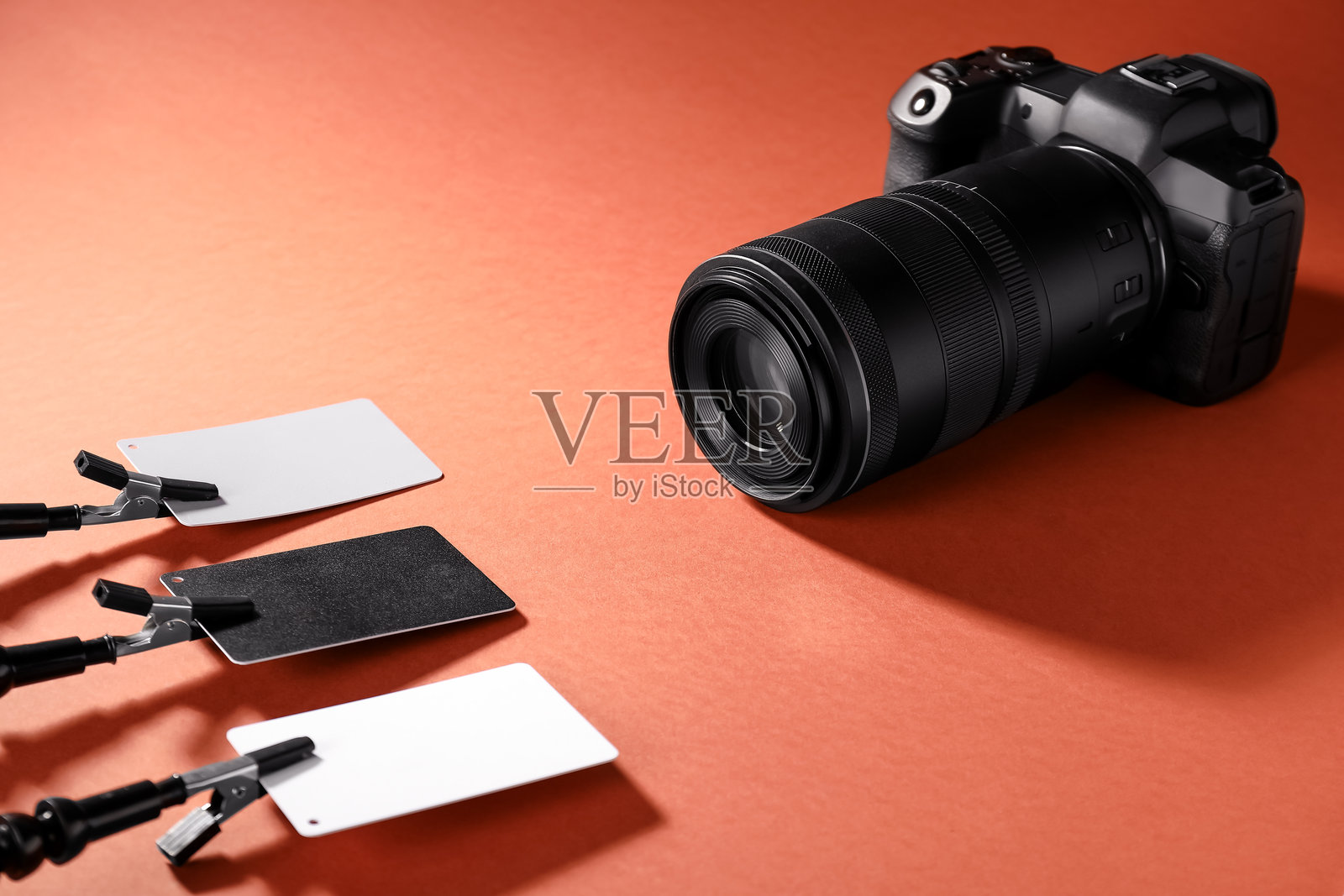 红色背景上的白平衡校准卡和相机照片摄影图片