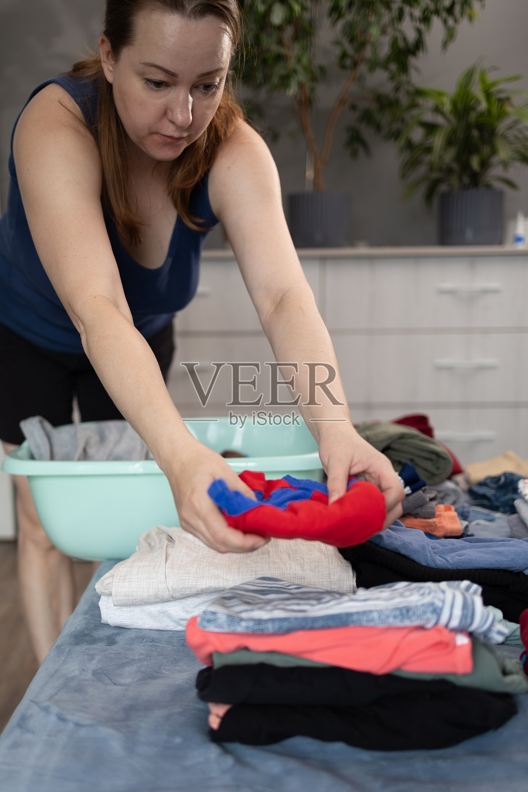 在温馨的家居环境中将洗衣服整理成整齐的堆，同时处理家务琐事照片摄影图片