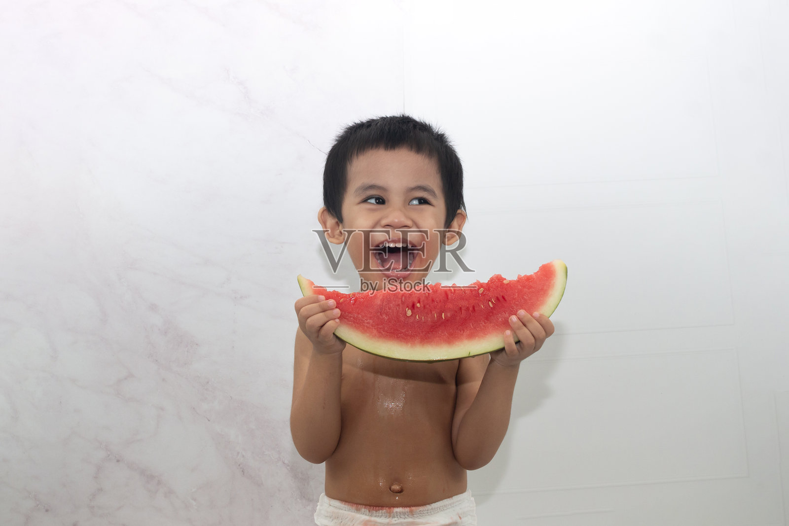 亚洲男孩手持西瓜片。照片摄影图片