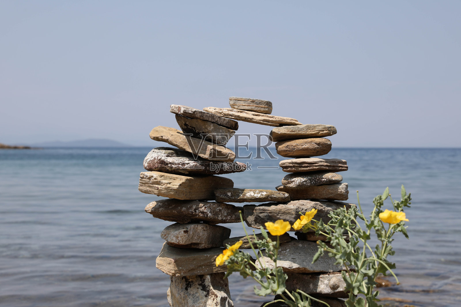 海滩上的岩石雕塑与花卉装饰照片摄影图片