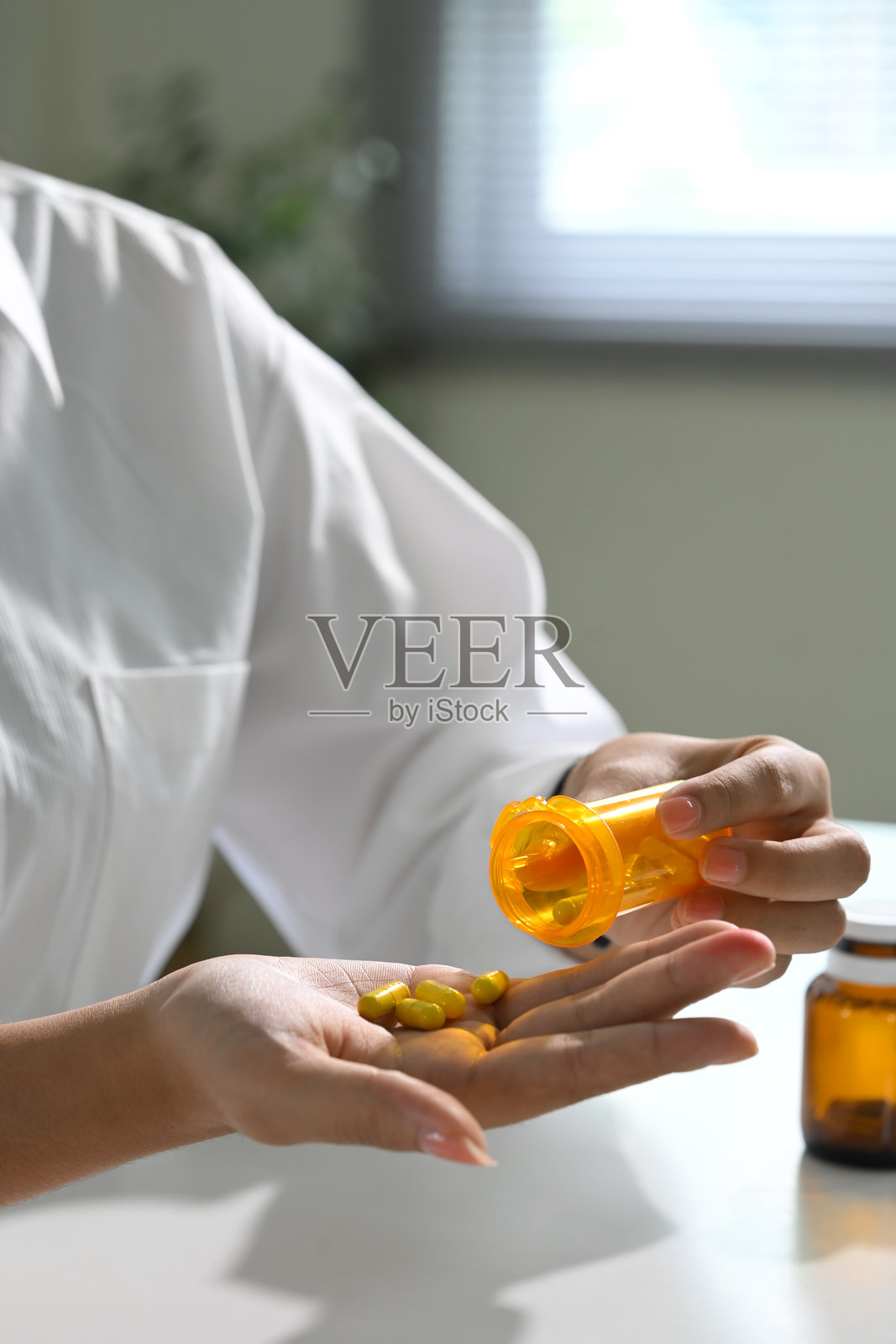 女性从处方瓶中倒出药丸，服用每日药物。健康护理概念照片摄影图片