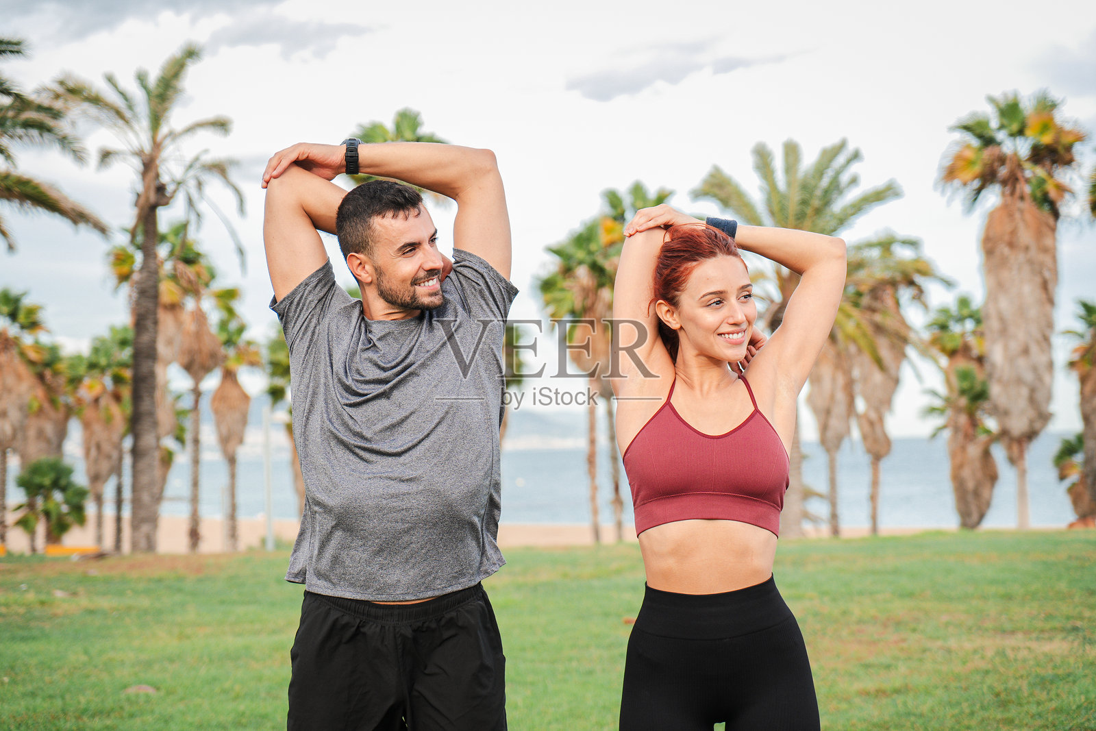 活力四射的情侣在海岸线上进行清新而充满活力的拉伸练习，以增强柔韧性并促进整体健康，同时享受彼此的陪伴和激励。照片摄影图片