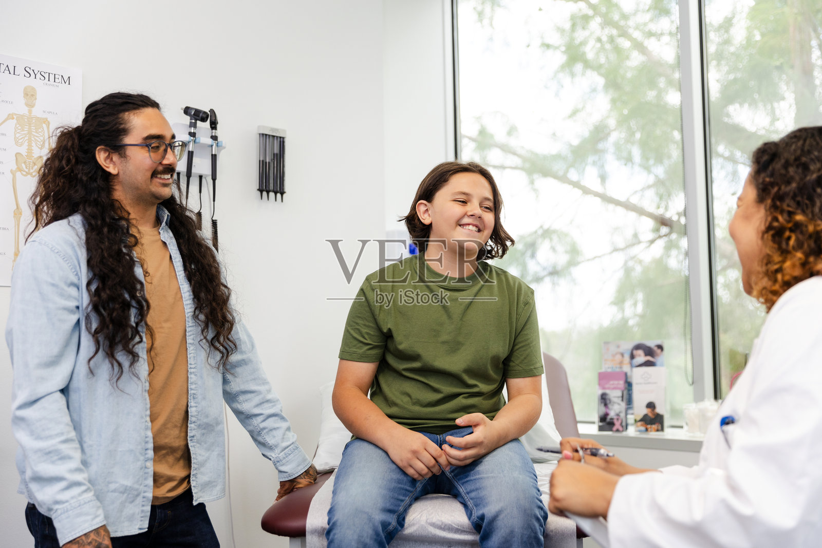 男孩和父亲在办公室与女医生交谈照片摄影图片