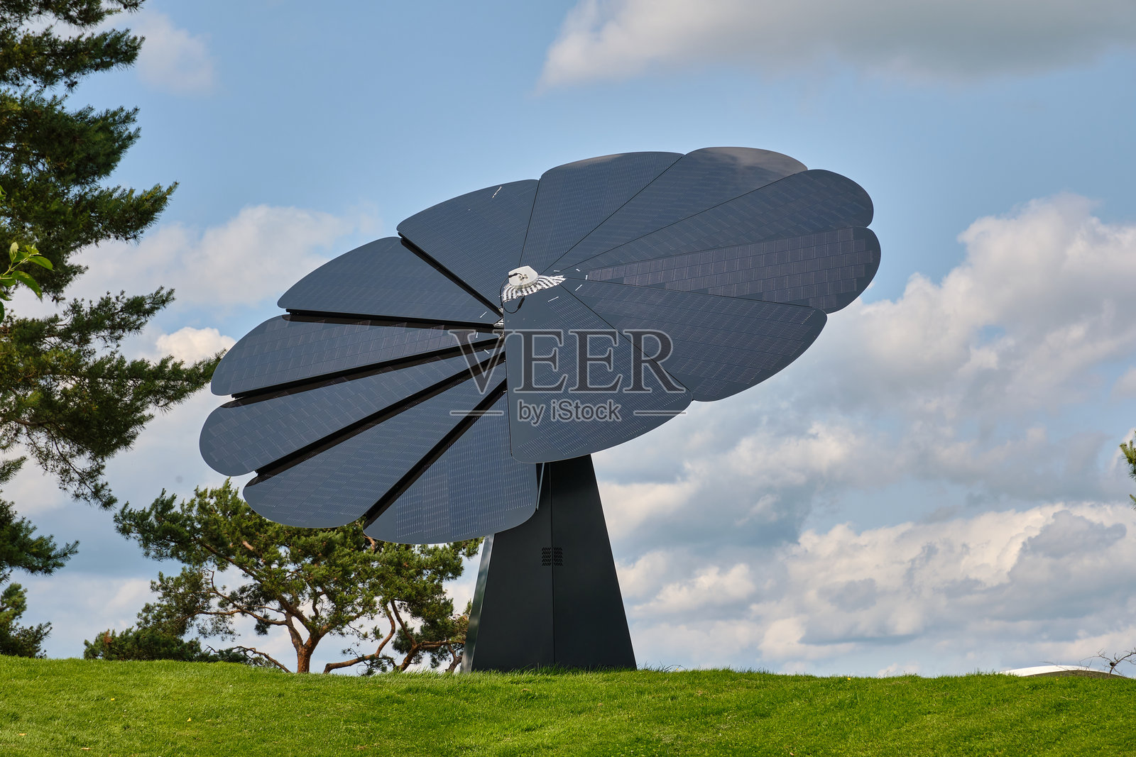 现代太阳能花卉装置位于蓝天白云下的绿色山丘上照片摄影图片