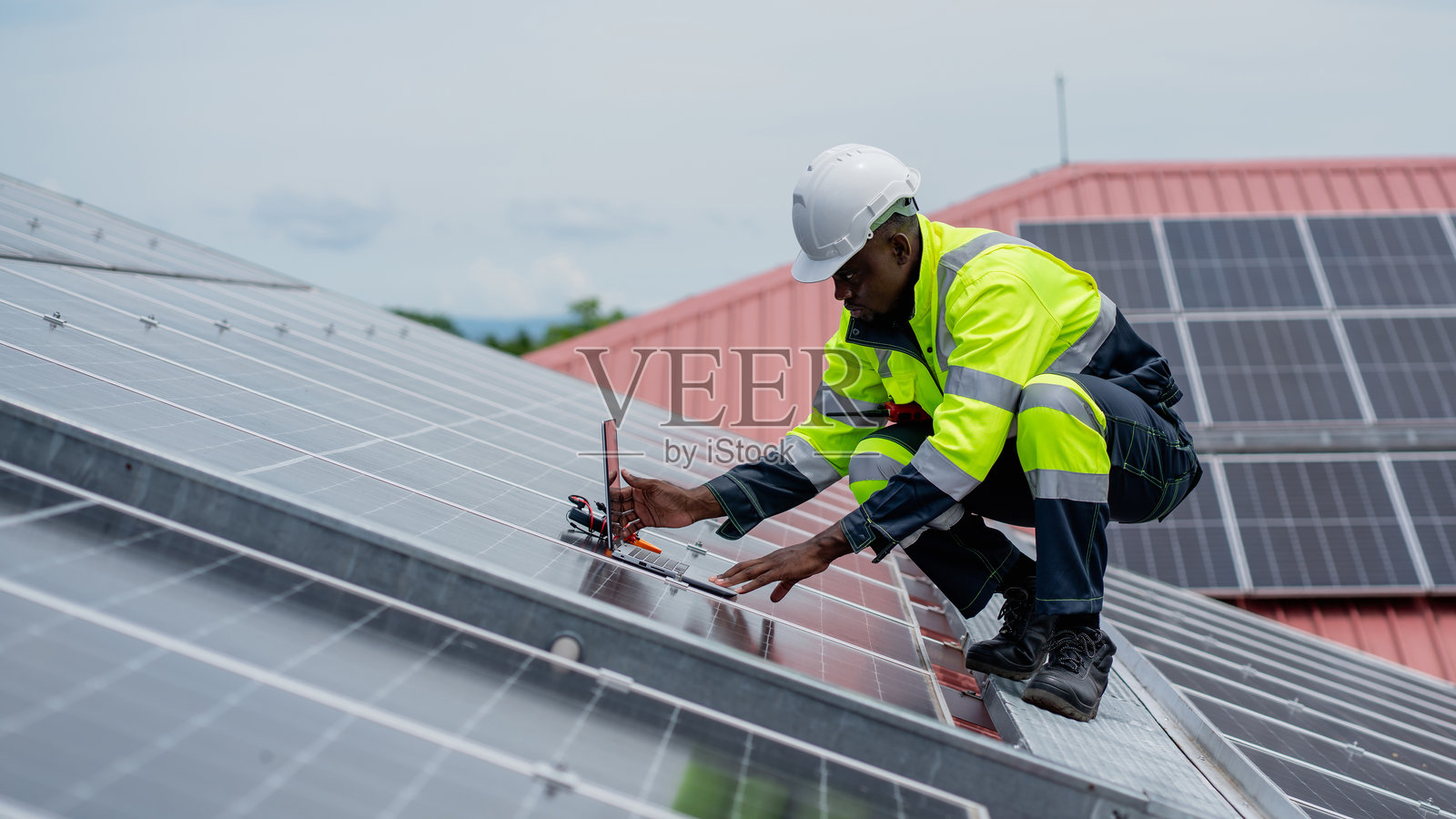 服务工程师在屋顶检查太阳能电池以进行维护，查看是否有损坏的部件。工程师正在安装太阳能板。清洁能源概念。照片摄影图片