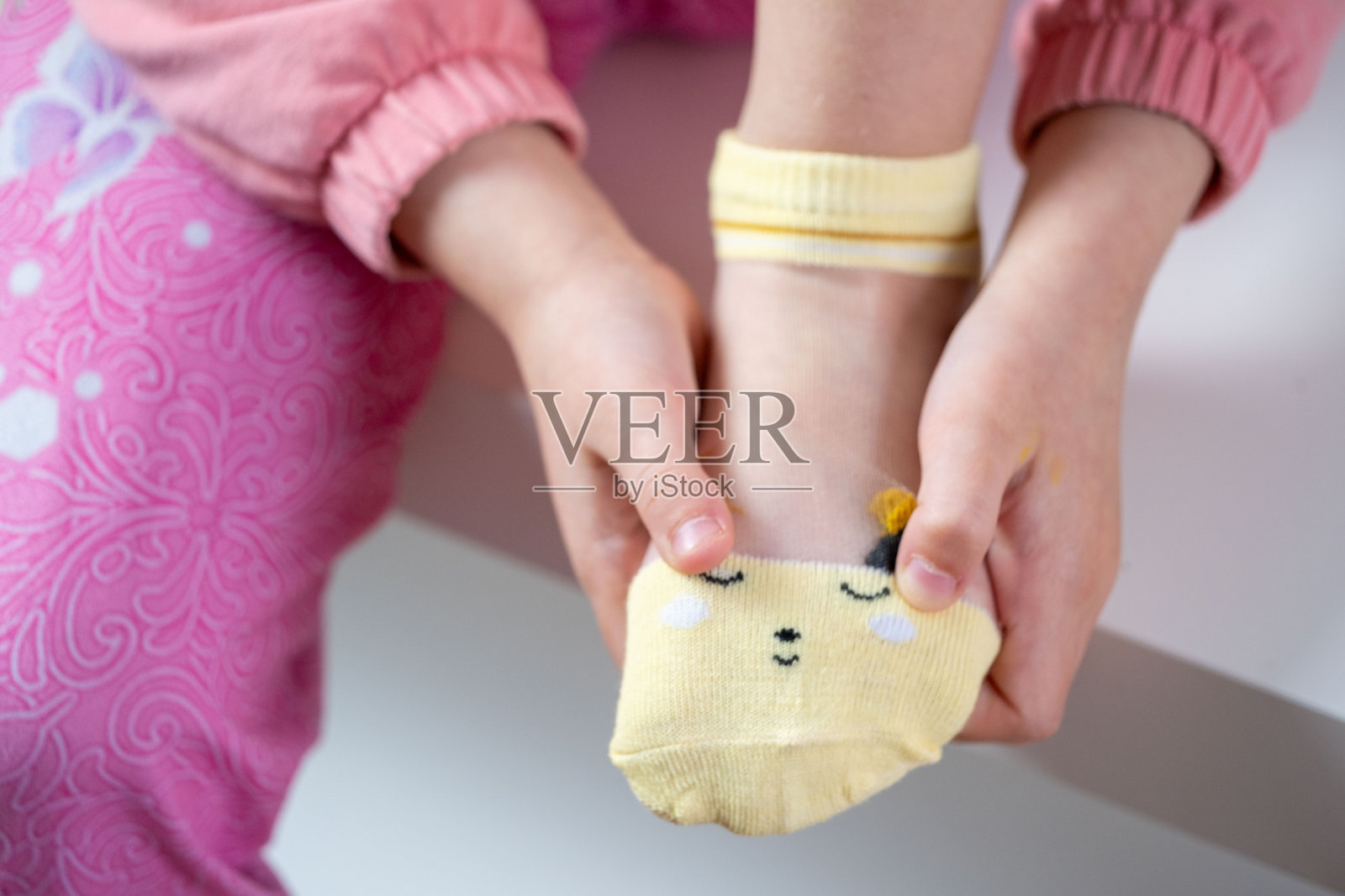 幼儿园女孩学习独立穿衣，穿袜子，年轻孩子实现自我穿衣里程碑，精细运动发展照片摄影图片