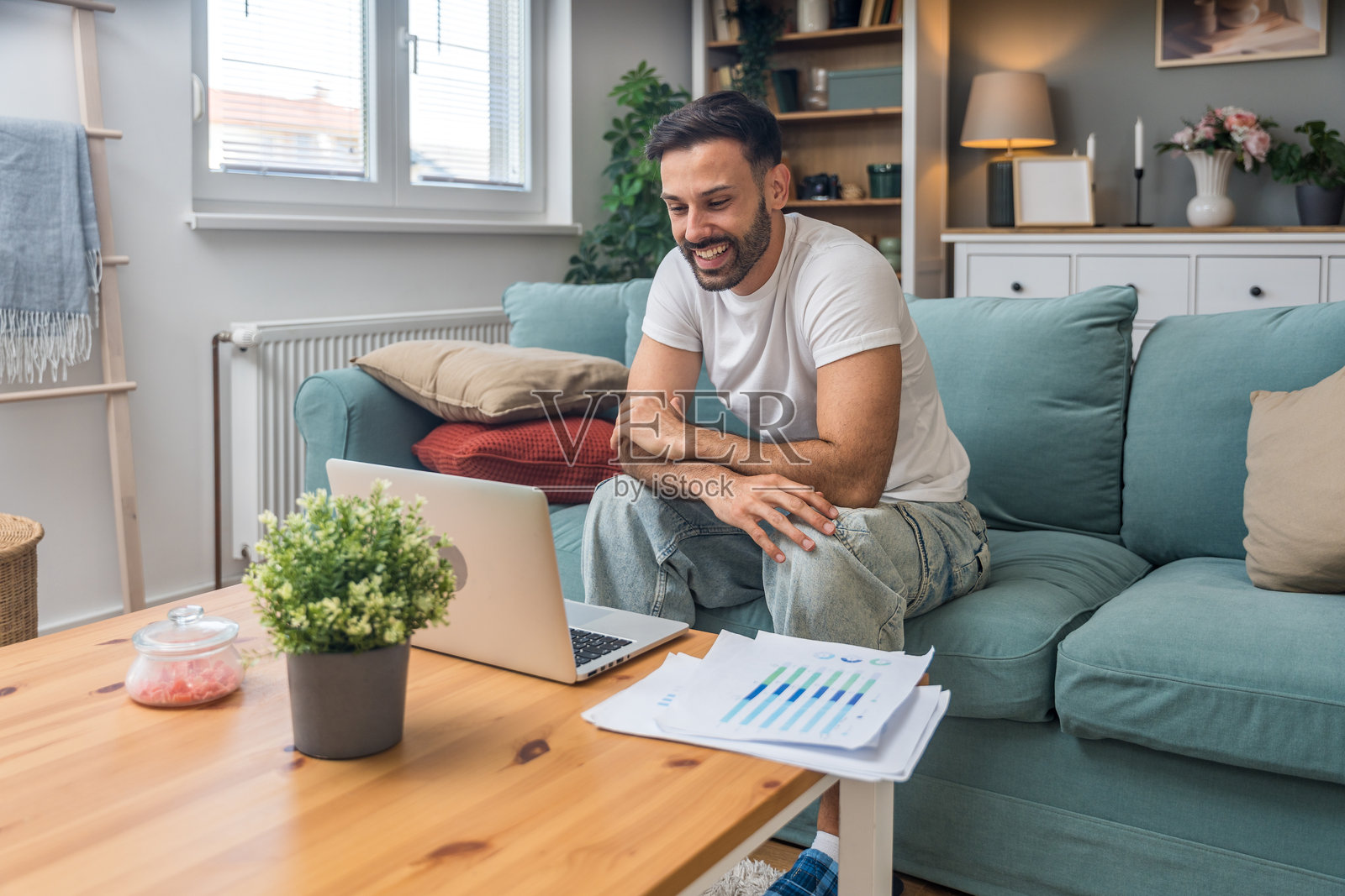 年轻的商业人士，小型初创公司的老板，在家工作，查看图表和笔记本电脑上的财务数据。创新的年轻自由职业男性正在计算新产品策略的成本和开支。照片摄影图片