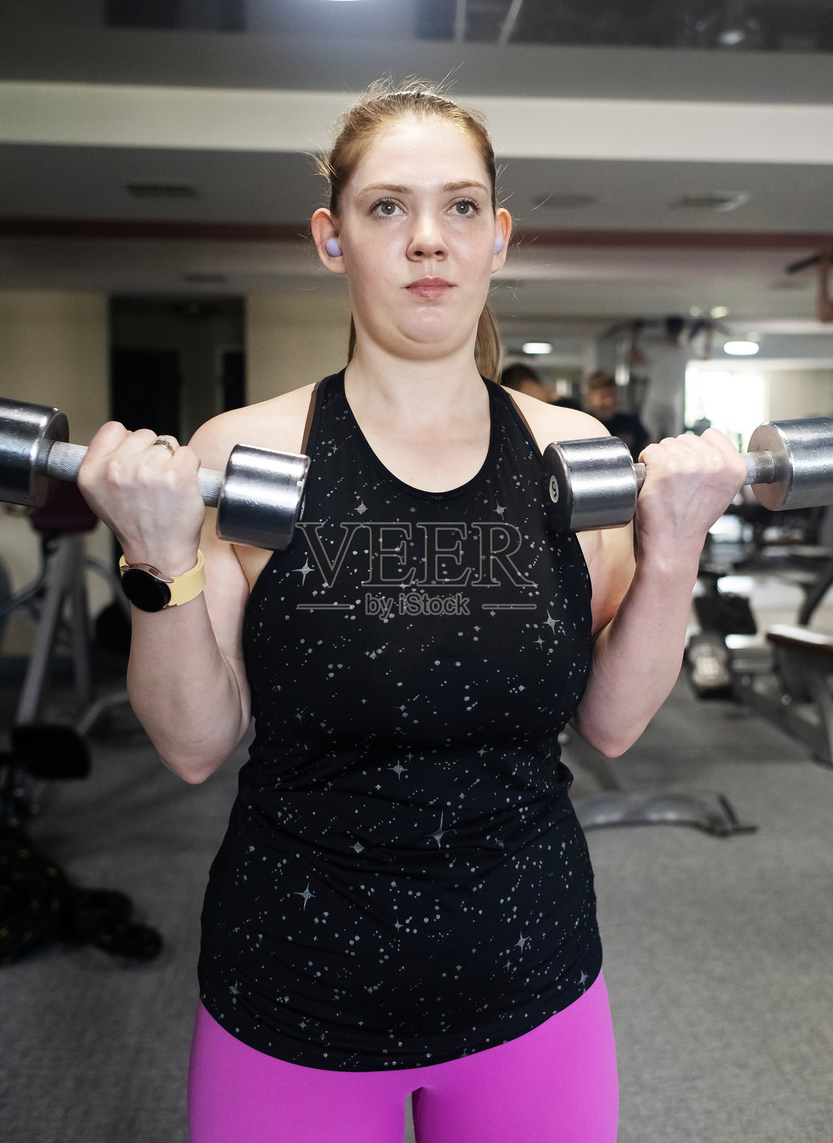普通女性在健身房使用哑铃锻炼。减肥锻炼。增强身体和健康生活方式。照片摄影图片