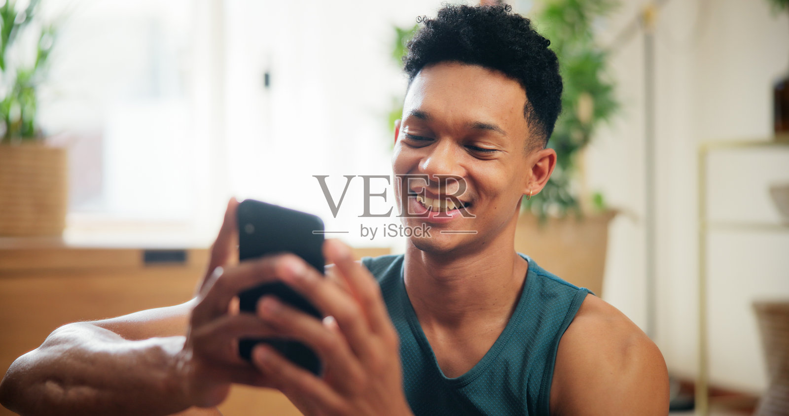 家中，男性与智能手机快乐地进行健身、虚拟锻炼，并浏览网站应用。房子里，男性休息时使用手机社交媒体，获取锻炼建议，面带微笑，享受科技。照片摄影图片