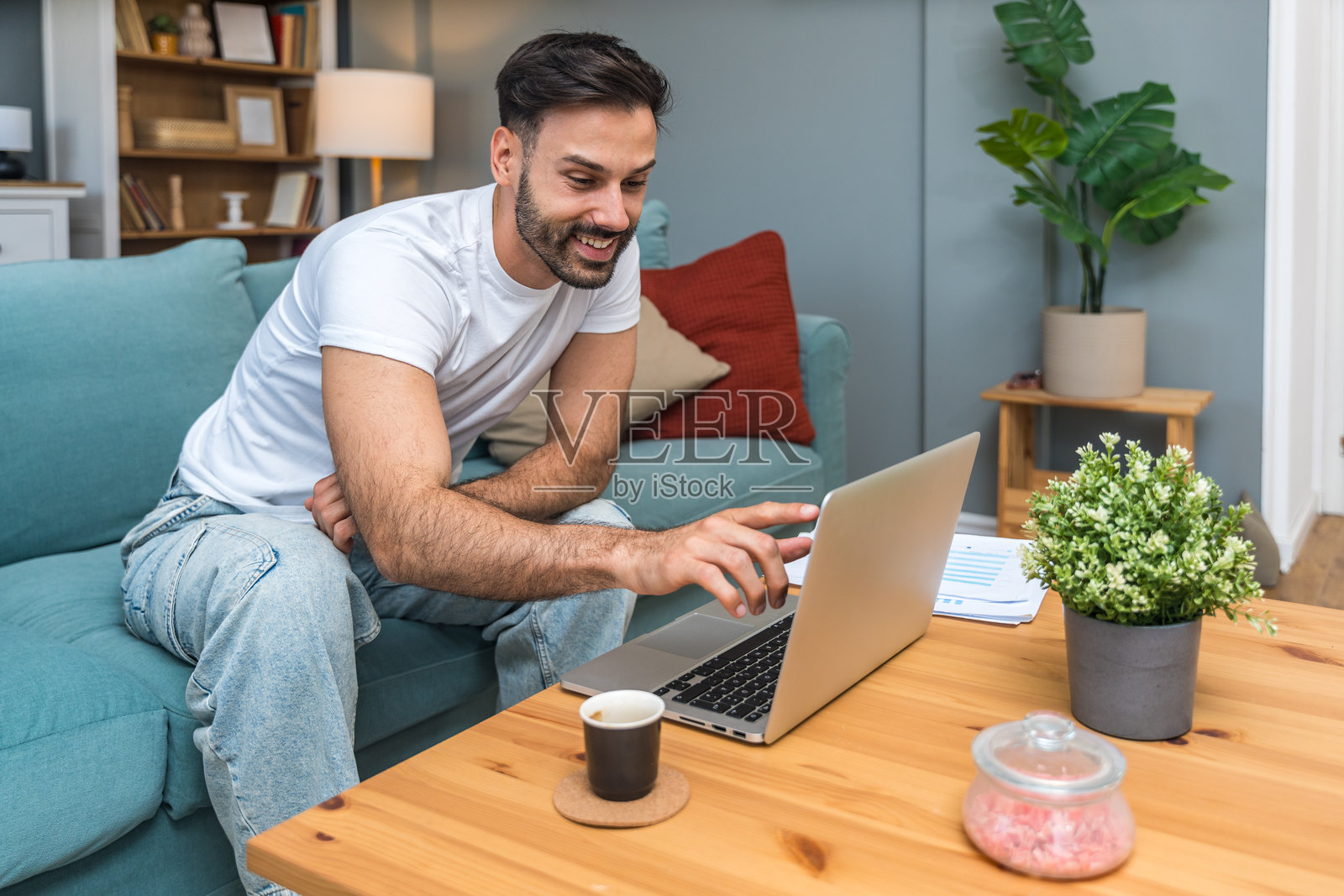 年轻的商业人士，小型创业公司的老板，在家工作，查看图表和笔记本电脑上的财务数据。创新的年轻自由职业男性正在计算新产品策略的成本和开支。照片摄影图片