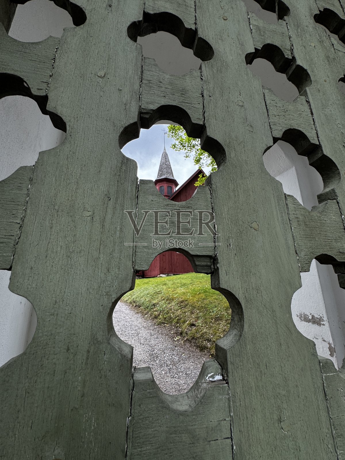 通过古老的绿色木栅栏看到的法格尔维克教堂塔楼——芬兰南部遗产的创意视角。照片摄影图片