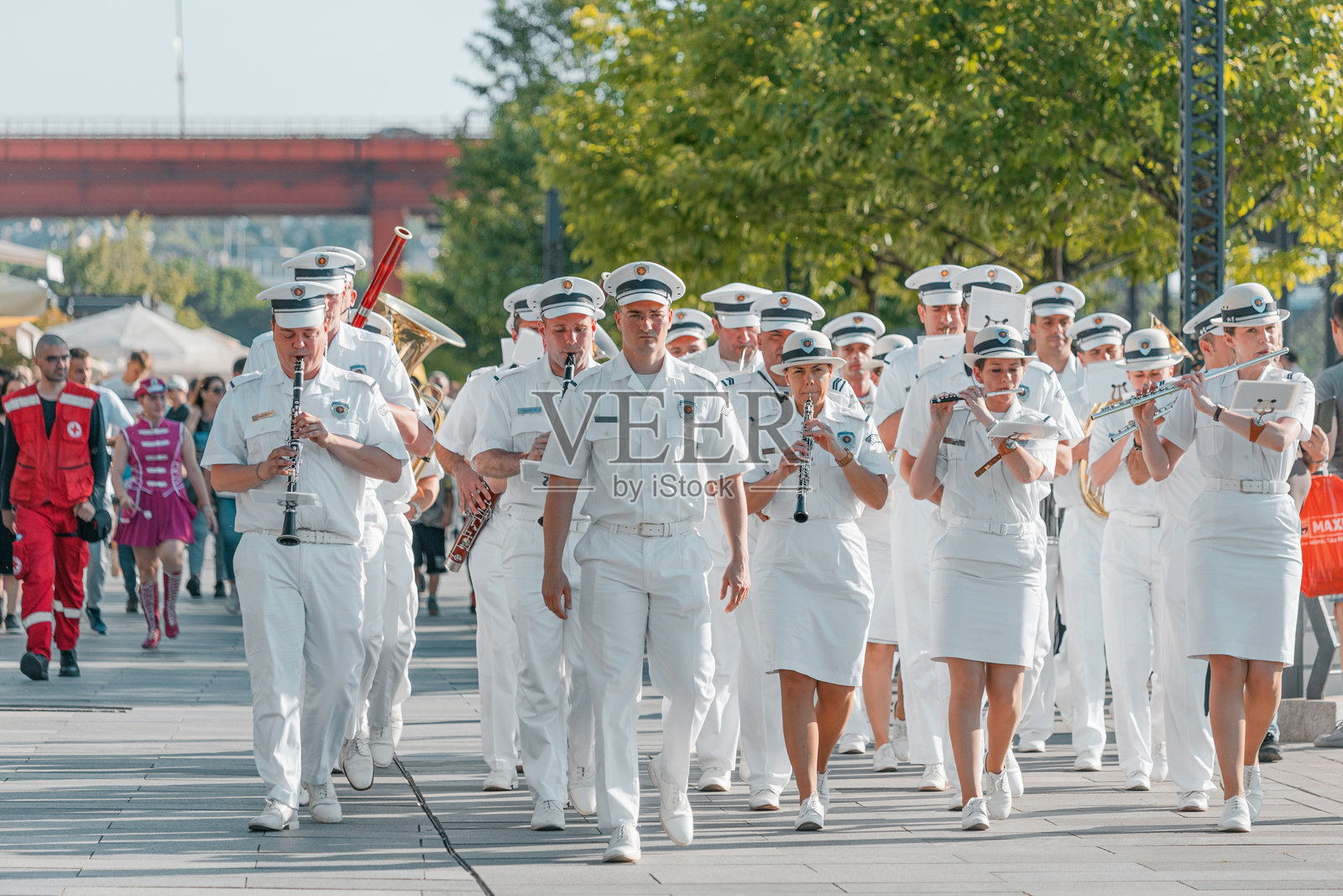 身穿整洁白色制服的音乐家们正在行进并演奏各种吹奏乐器照片摄影图片