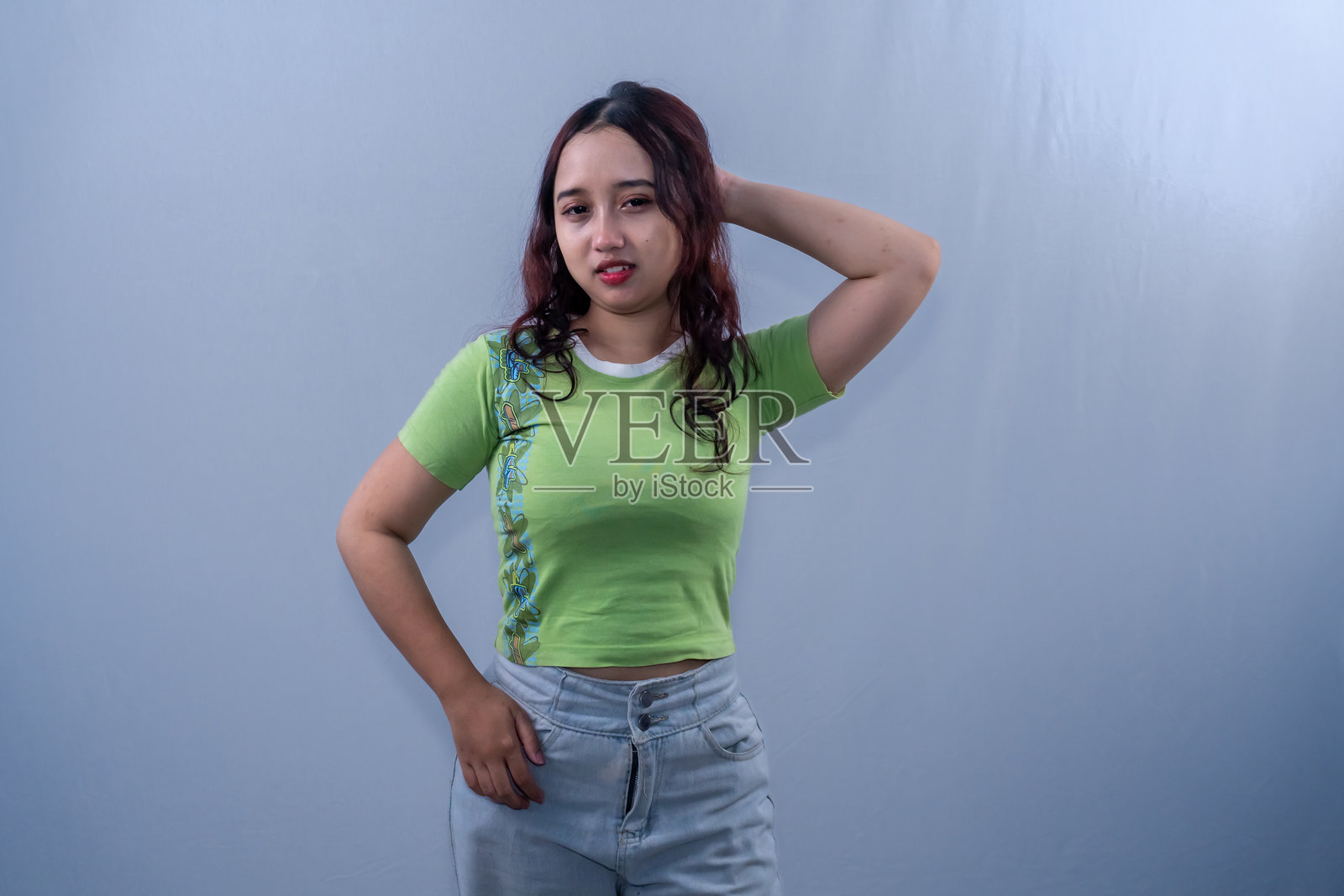 穿着绿色裙子的印尼亚洲女性微笑着托着头。照片摄影图片