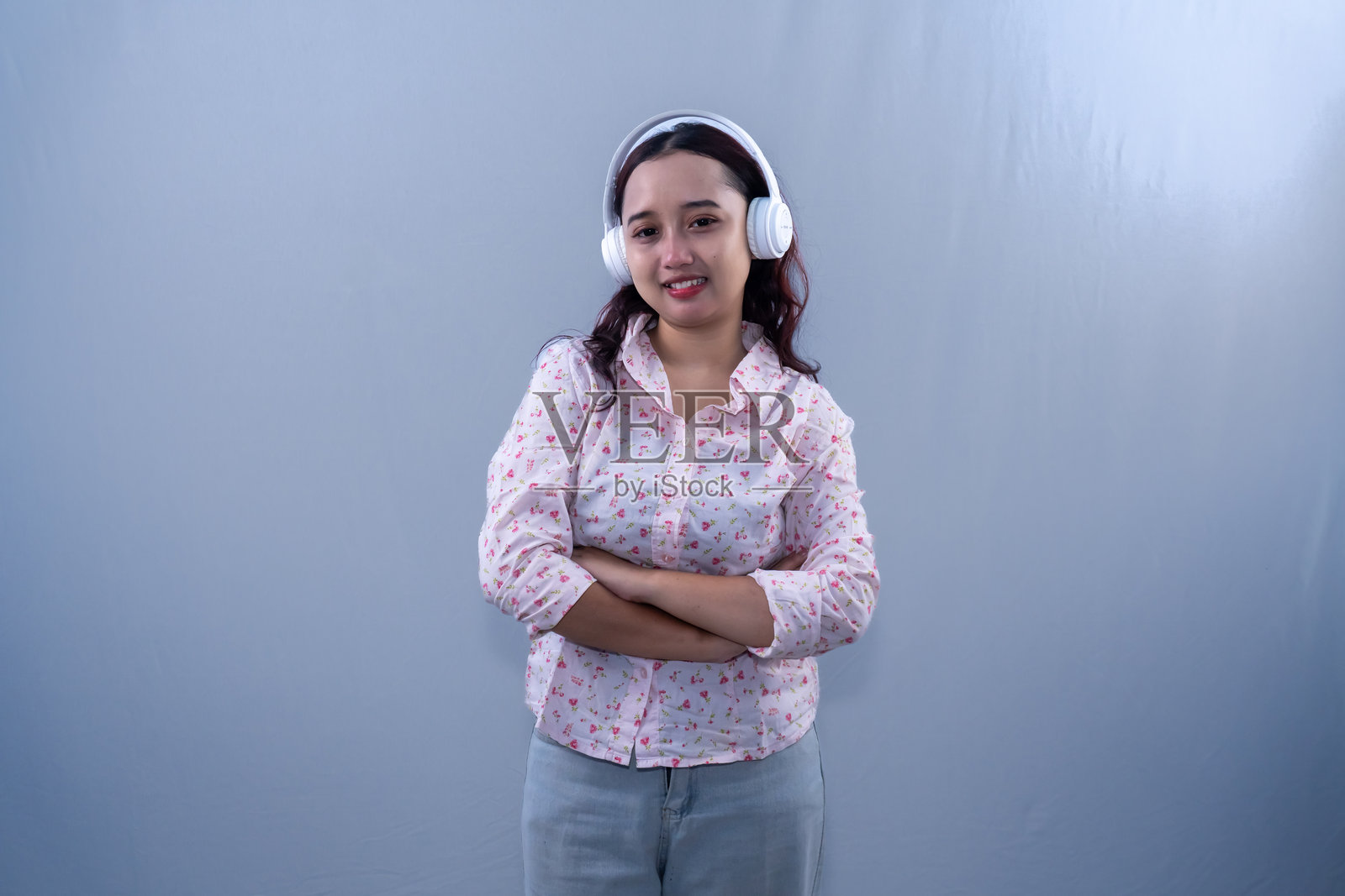 身穿白色花卉连衣裙的印尼亚洲女性戴着耳机听音乐照片摄影图片