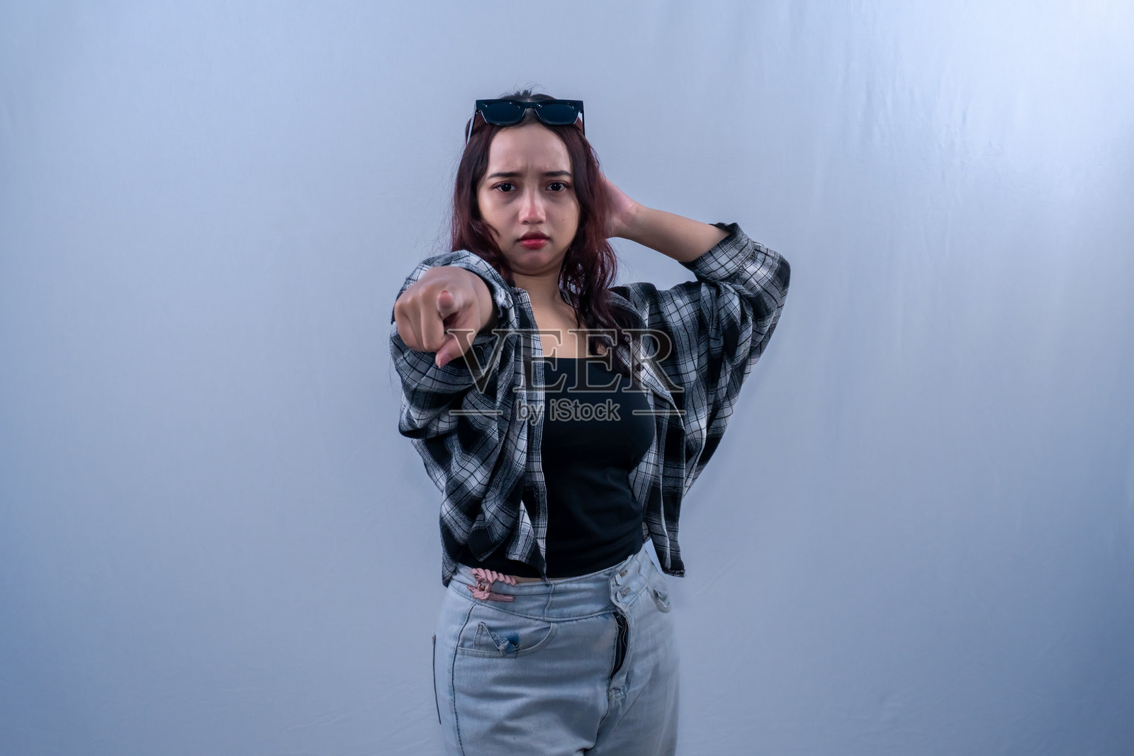 身穿黑色格子裙的印尼亚洲女性向前指。照片摄影图片