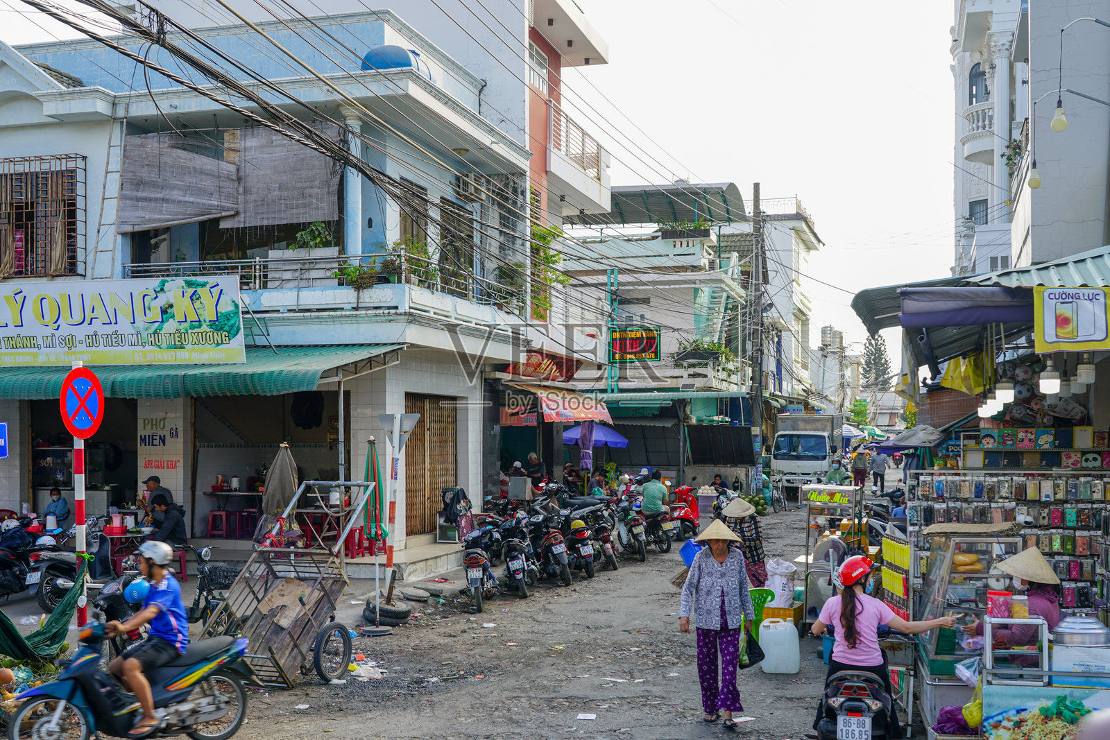典型的街道场景,市场摊位、电动车和当地购物者照片摄影图片