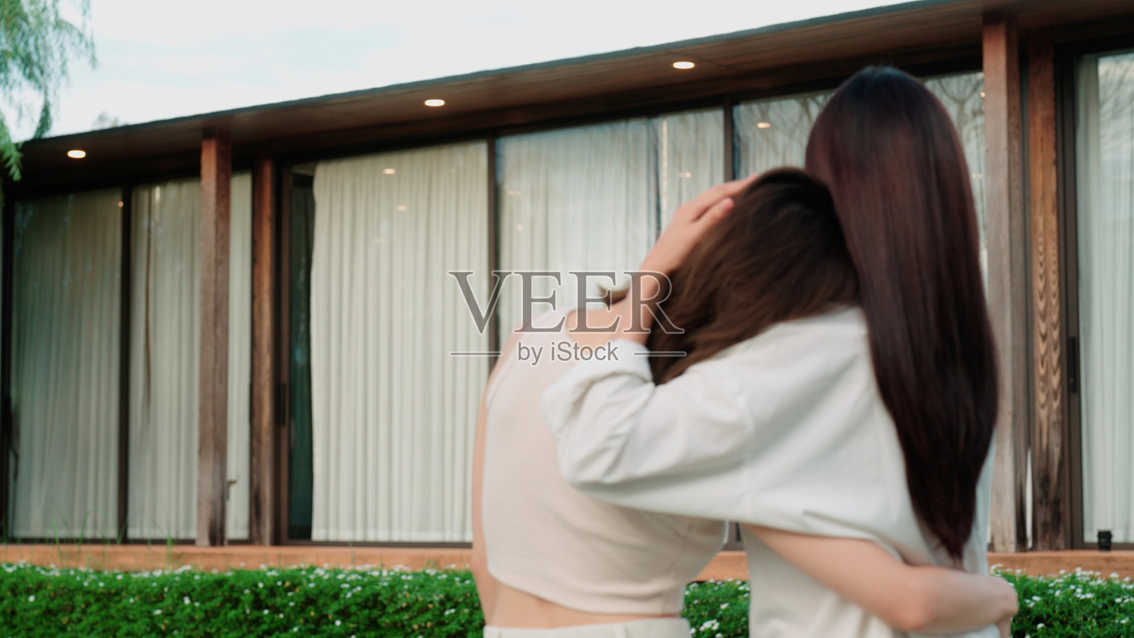 一对女性情侣背对着新家站立。照片摄影图片