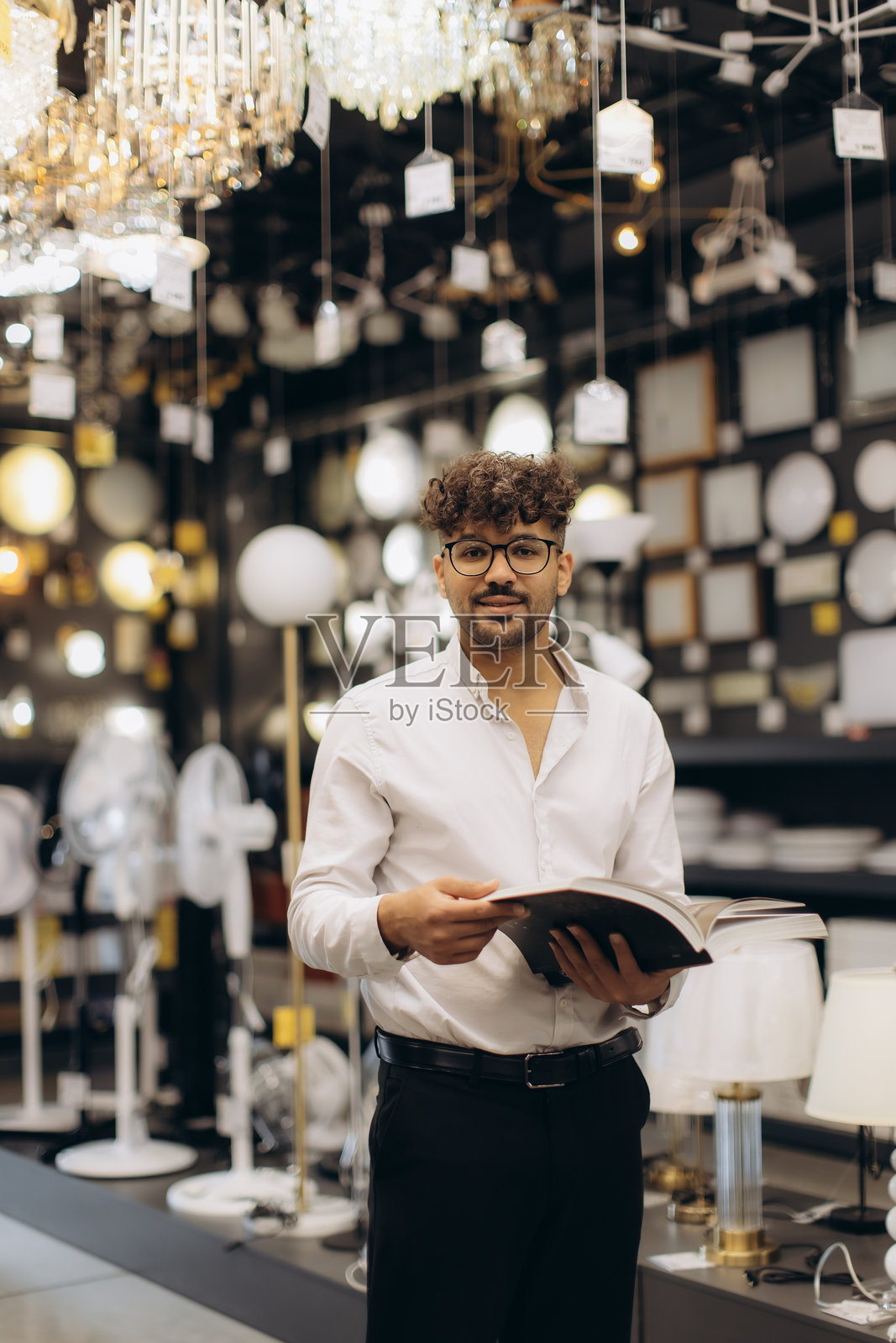 在照明商店里，男子手持展示各种灯具的目录照片摄影图片