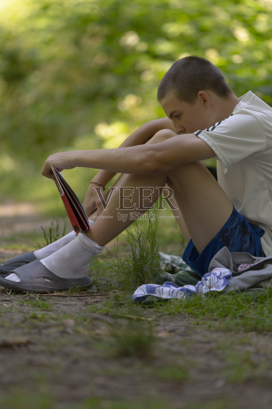 一个小男孩坐在地上，认真地系着他的袜子。照片摄影图片