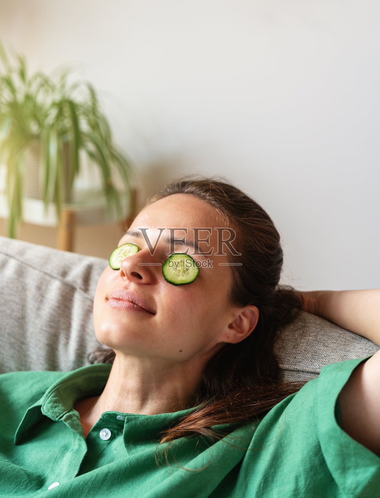 女人在家中沙发上放松，敷着黄瓜眼膜照片摄影图片