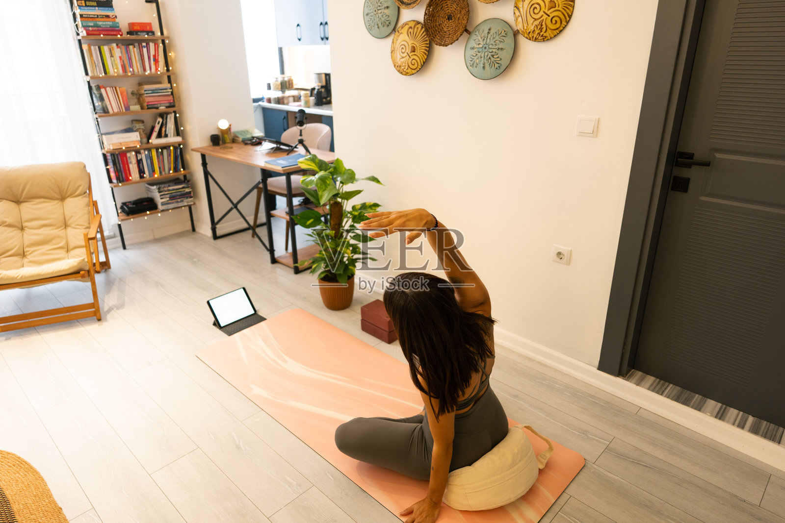 年轻女性在家中跟随平板电脑上的在线教程练习瑜伽照片摄影图片