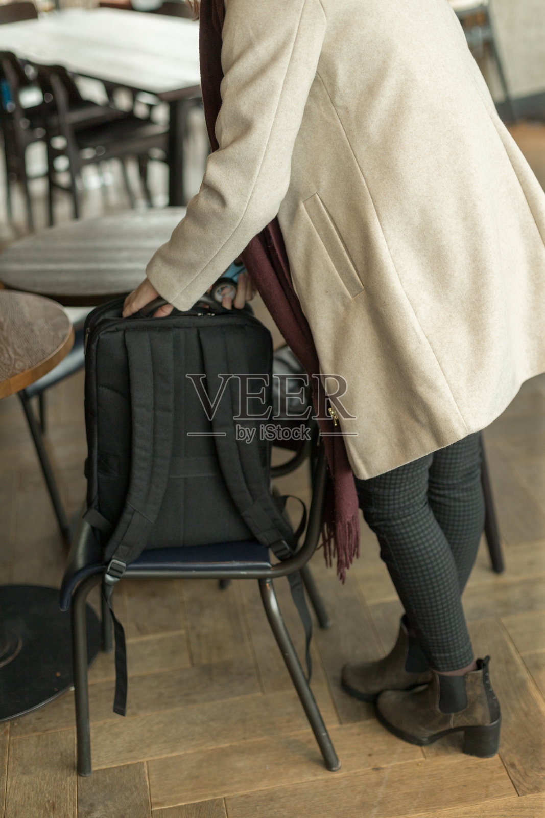 一位女性正在餐厅里小心翼翼地把背包放在椅子上。照片摄影图片