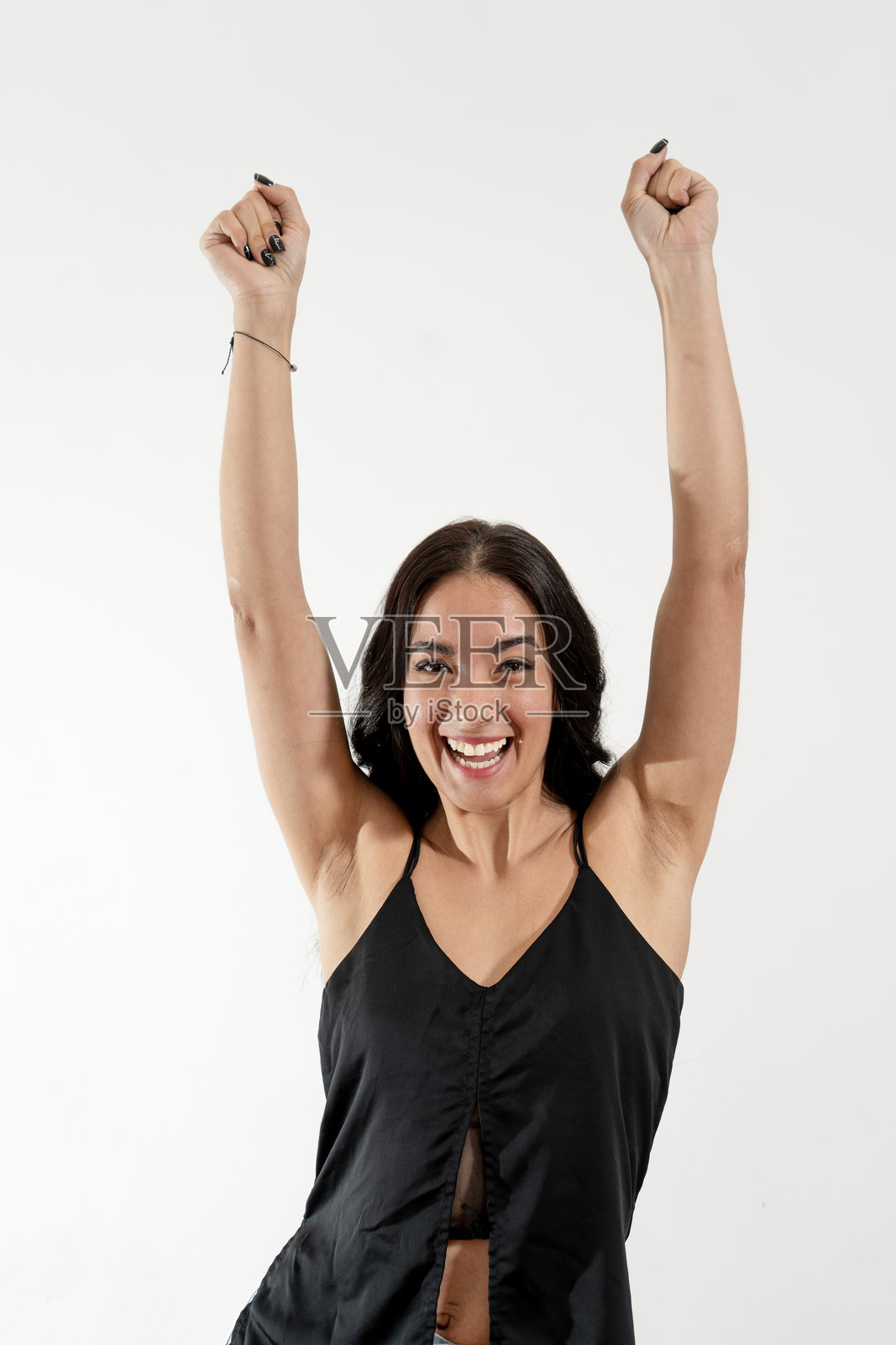 年轻女性举起双臂，握紧拳头，表达喜悦和兴奋。照片摄影图片