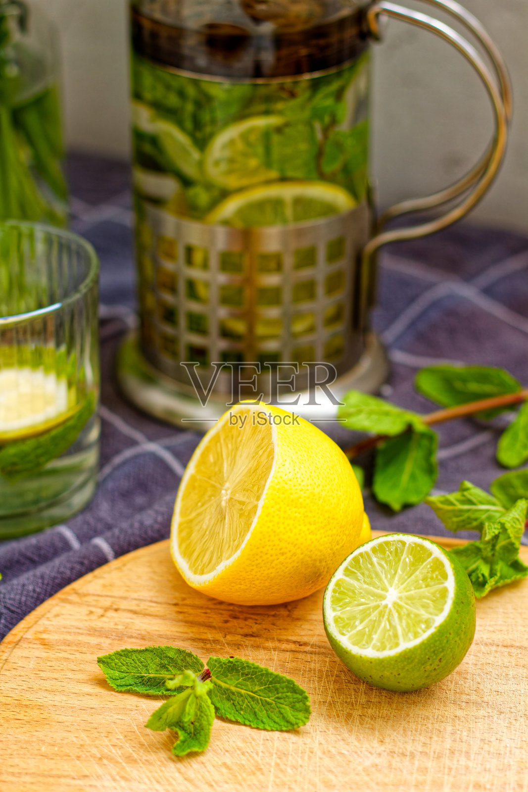 清爽的夏季饮品准备，配有柠檬、青柠和薄荷叶，放在木板上。照片摄影图片