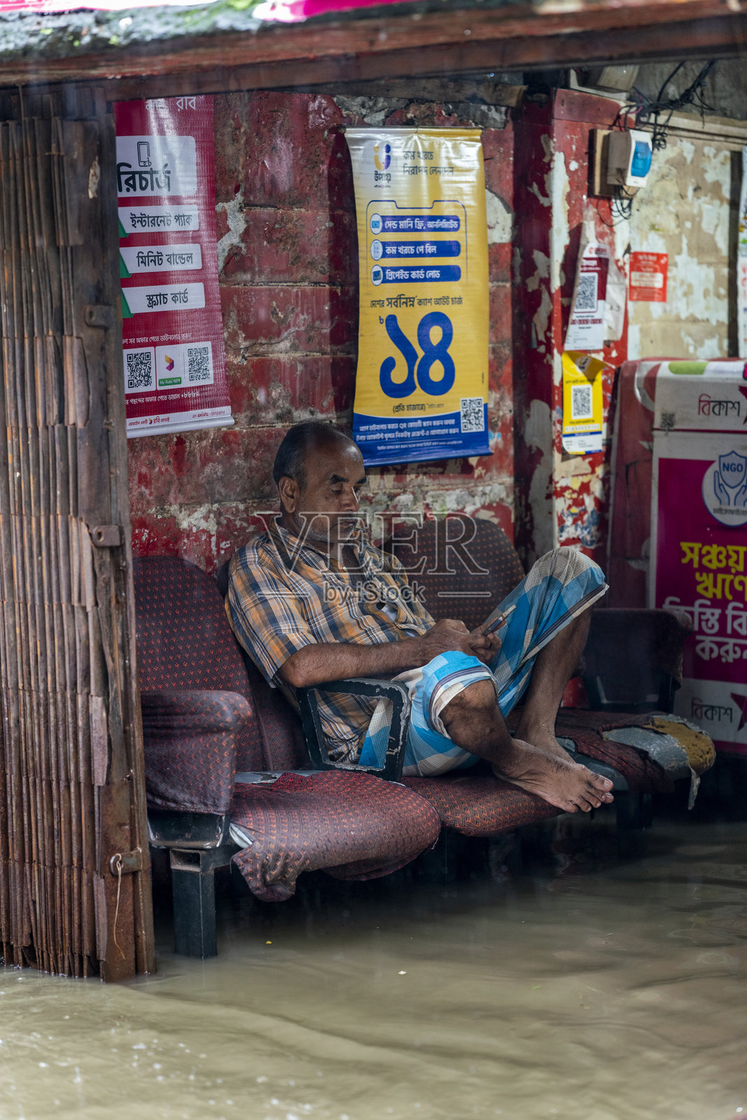 男子坐在被淹没的地区。水涝是孟加拉国的一个严重问题,尤其是在雨季,影响着主要城市中心。照片摄影图片