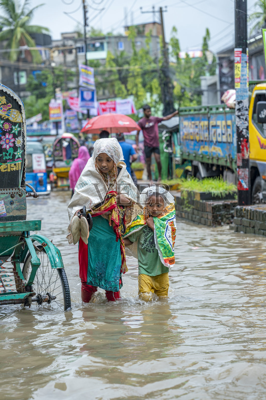 孩子们在城市的淹水街道中涉水而行。水涝是孟加拉国的一个严重问题，尤其是在雨季期间。照片摄影图片
