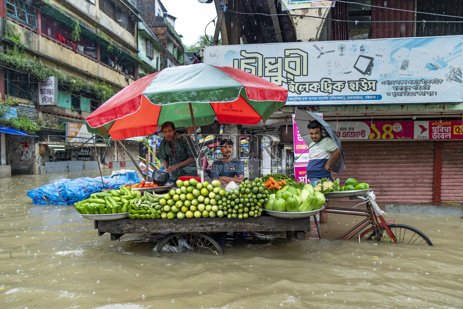 洪水中的街市摊贩在水中出售农产品。孟加拉国吉大港市的积水问题屡见不鲜,尤其是在雨季。照片摄影图片