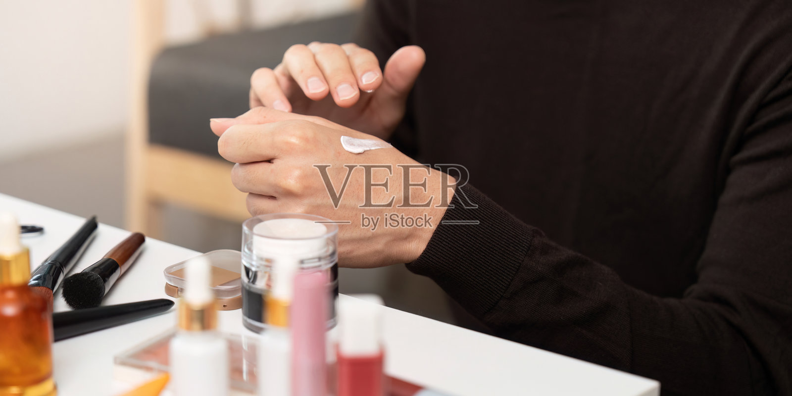 护肤程序。年轻男子在舒适的家居环境中涂抹保湿霜。照片摄影图片